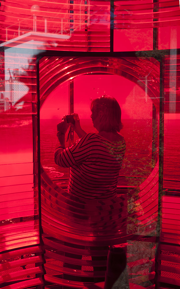 Woman on deck outside lighthouse, shot through lighthouse lense